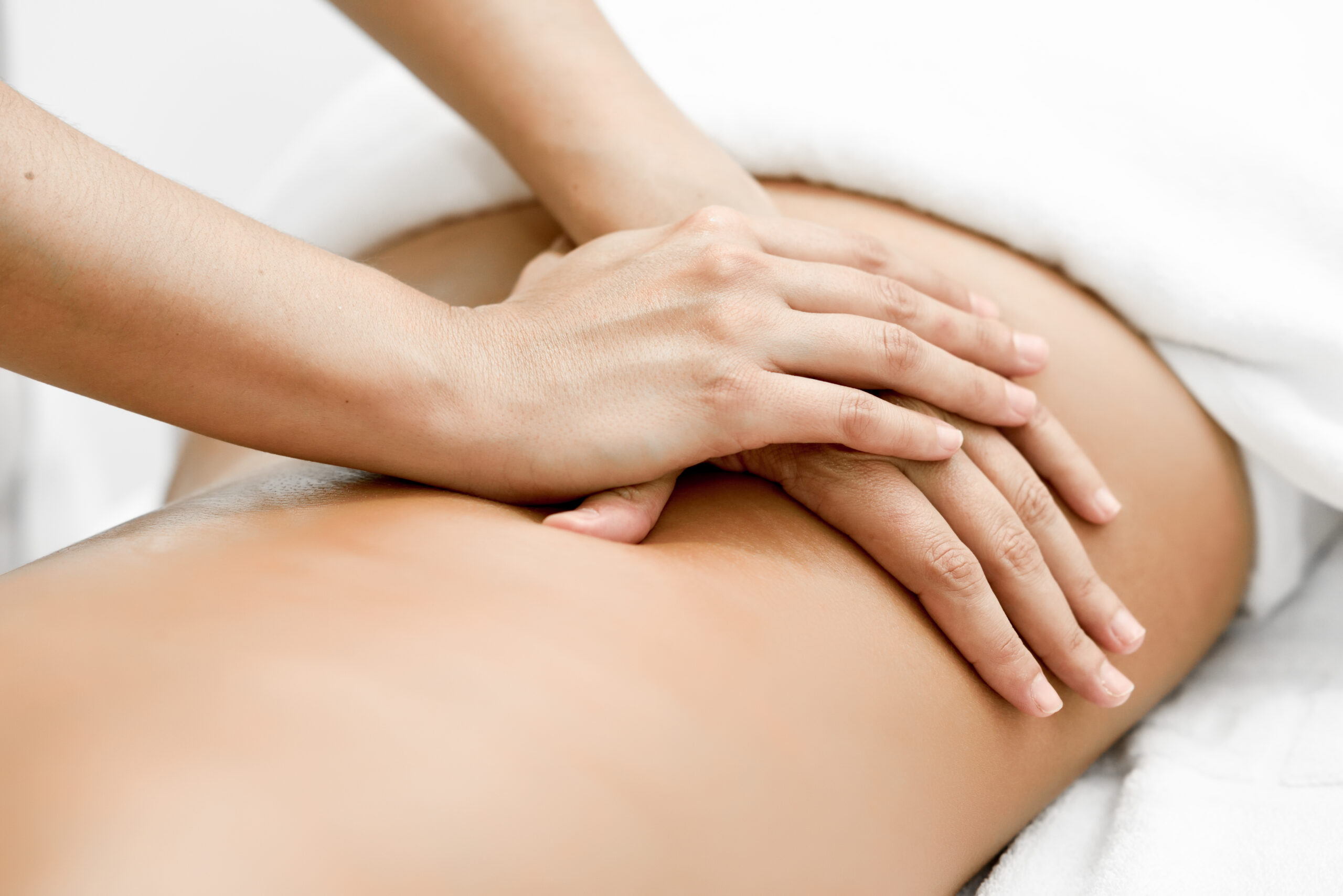 Young woman receiving a back massage in a spa center. Female patient is receiving treatment by professional therapist.